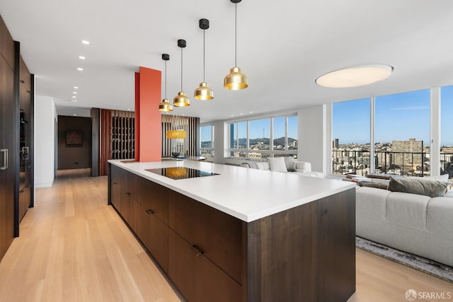 kitchen featuring black electric cooktop, light hardwood / wood-style flooring, decorative light fixtures, and a spacious island