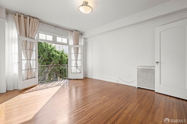 unfurnished room with radiator heating unit, baseboards, and wood finished floors