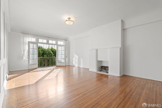 unfurnished living room with a fireplace, wood finished floors, and baseboards