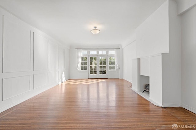 unfurnished living room with wood finished floors, a fireplace, and a decorative wall