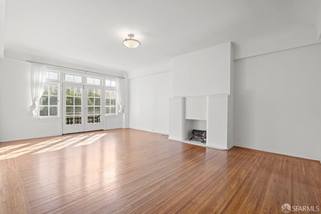 unfurnished living room with a fireplace, baseboards, and wood finished floors