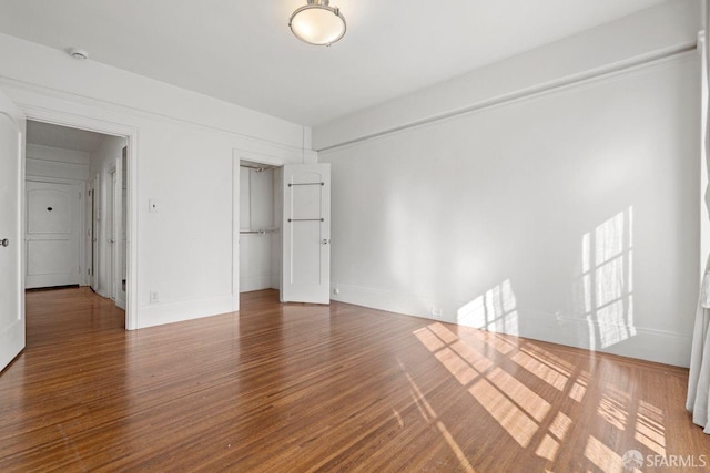 unfurnished bedroom featuring wood finished floors, a closet, and baseboards