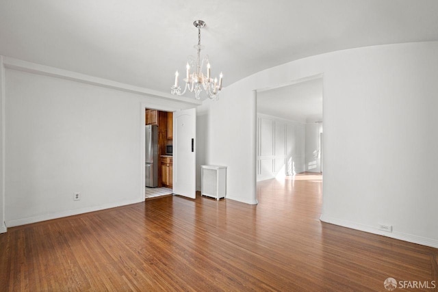 spare room featuring baseboards, wood finished floors, and vaulted ceiling