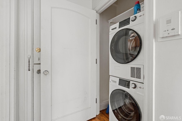 laundry room with stacked washer / dryer, laundry area, and wood finished floors