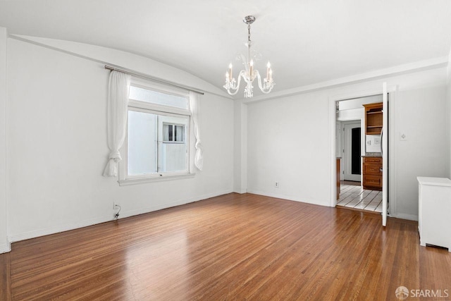 unfurnished room with a chandelier, vaulted ceiling, baseboards, and wood finished floors