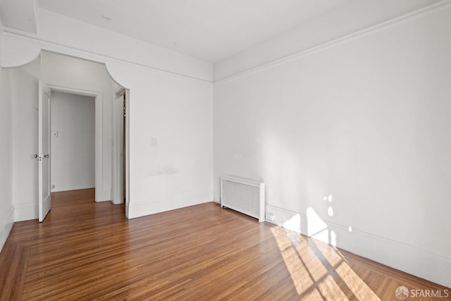 spare room with radiator and wood finished floors