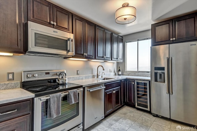 kitchen with sink, beverage cooler, dark brown cabinets, and appliances with stainless steel finishes