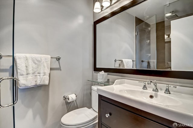 bathroom with walk in shower, vanity, and toilet