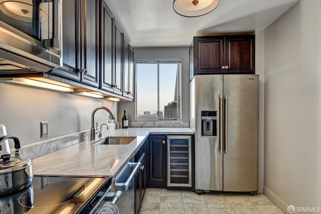 kitchen featuring stainless steel appliances, light stone counters, sink, and wine cooler