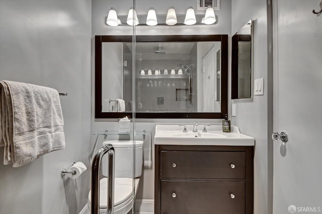 bathroom featuring toilet, vanity, and a shower with shower door