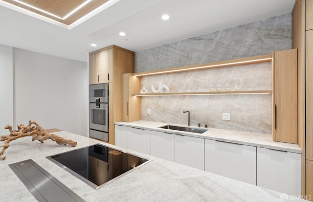 kitchen featuring black electric stovetop, tasteful backsplash, light brown cabinetry, and sink