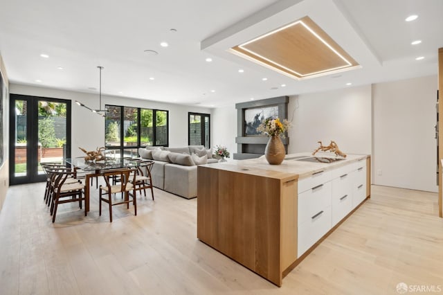 kitchen featuring a kitchen island, decorative light fixtures, light hardwood / wood-style flooring, butcher block countertops, and white cabinetry