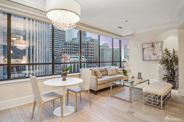 interior space featuring crown molding, baseboards, a chandelier, light wood-style floors, and a view of city