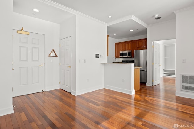 kitchen featuring appliances with stainless steel finishes, sink, dark hardwood / wood-style flooring, ornamental molding, and kitchen peninsula