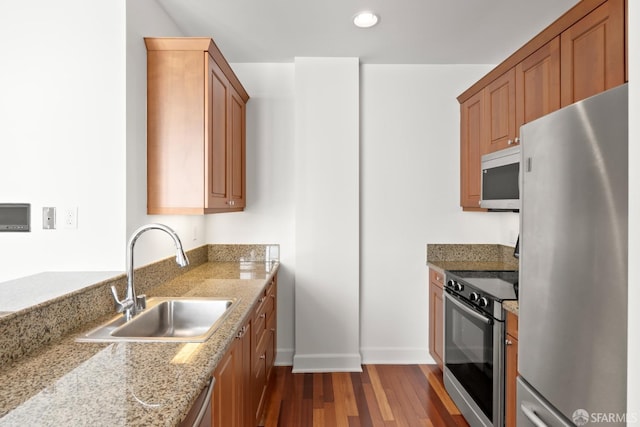 kitchen with light stone counters, stainless steel appliances, dark hardwood / wood-style flooring, and sink