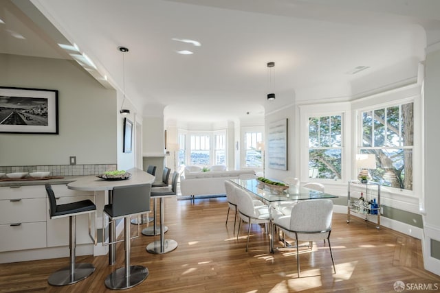 dining space with light hardwood / wood-style floors, crown molding, and a healthy amount of sunlight