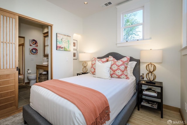 bedroom featuring ensuite bath and hardwood / wood-style floors