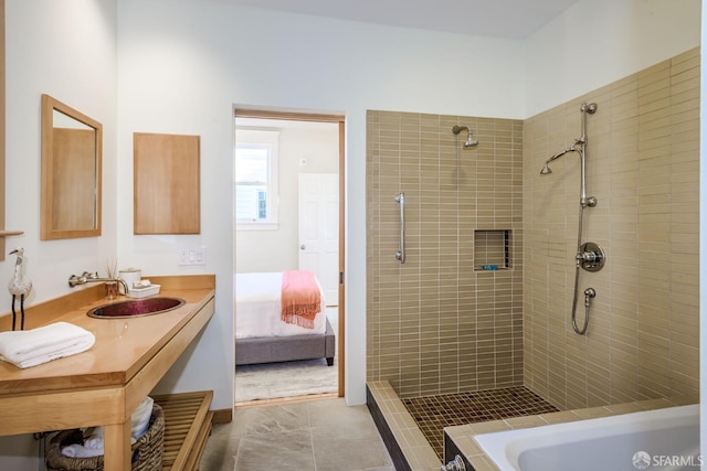 bathroom featuring tile patterned flooring, tiled shower, and sink