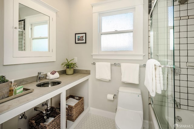 full bathroom with sink, tile patterned flooring, combined bath / shower with glass door, and toilet