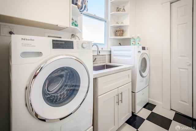 washroom with cabinets, washing machine and clothes dryer, and sink