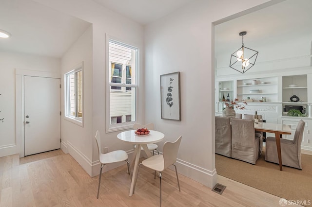 dining area featuring baseboards, visible vents, and light wood finished floors