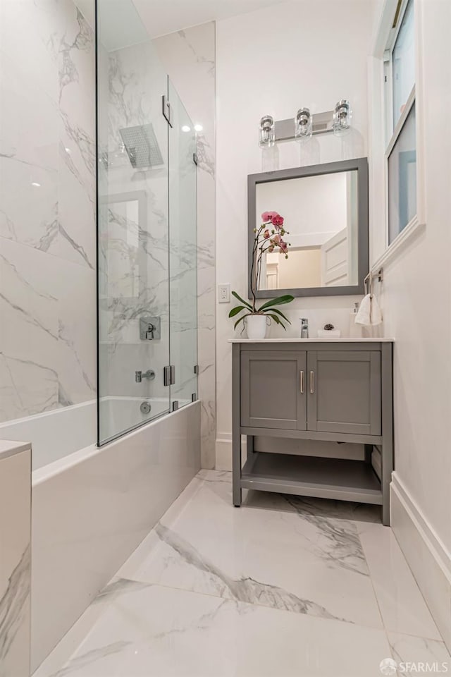 bathroom with marble finish floor, bath / shower combo with glass door, and vanity