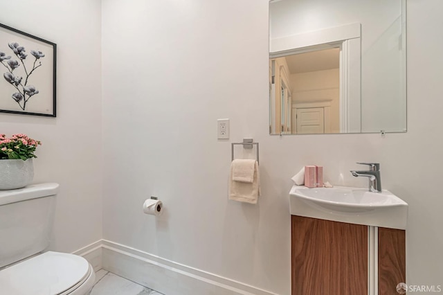 bathroom featuring baseboards, toilet, and vanity