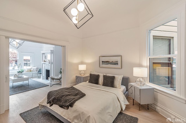 bedroom featuring a notable chandelier, baseboards, access to outside, and light wood finished floors