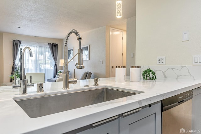 1396 El Camino Real Unit 110, Millbrae, CA 94030 - kitchen with stainless steel dishwasher, light stone countertops, gray cabinets, and a textured ceiling