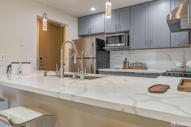 1396 El Camino Real Unit 110, Millbrae, CA 94030 - kitchen featuring wall chimney range hood, appliances with stainless steel finishes, gray cabinets, light stone countertops, and hanging light fixtures