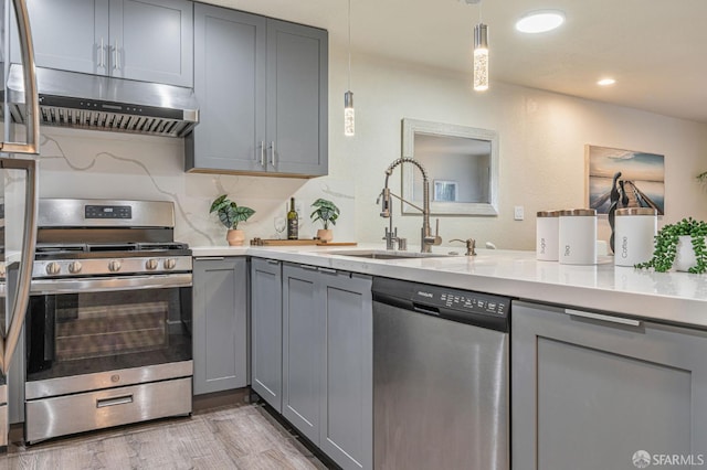 1396 El Camino Real Unit 110, Millbrae, CA 94030 - kitchen with appliances with stainless steel finishes, gray cabinets, light countertops, under cabinet range hood, and light wood-style flooring