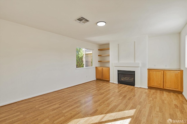 unfurnished living room with light wood-type flooring and built in features