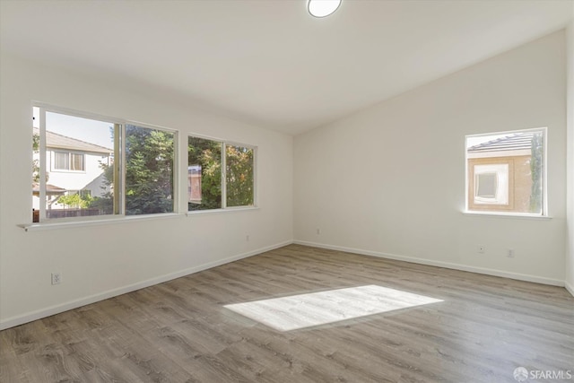 spare room featuring vaulted ceiling and light hardwood / wood-style flooring