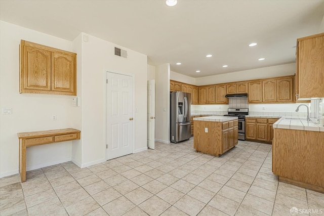 kitchen with tile counters, a center island, sink, light tile patterned floors, and appliances with stainless steel finishes