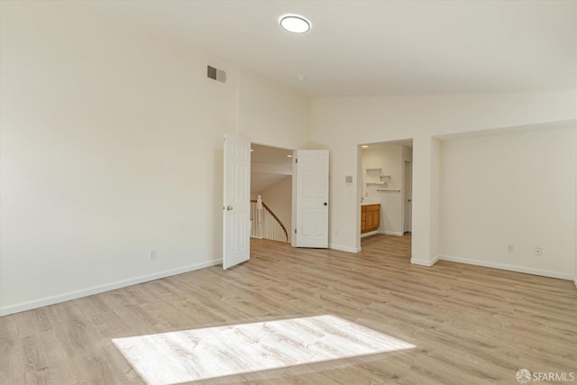 unfurnished bedroom with ensuite bathroom, light hardwood / wood-style flooring, and high vaulted ceiling