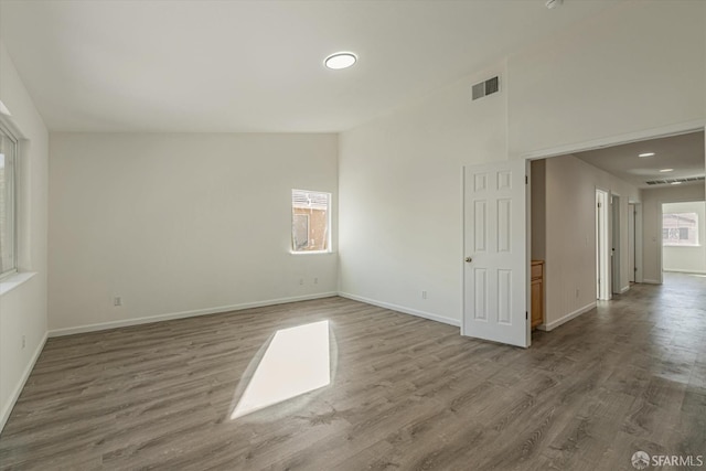 unfurnished room with lofted ceiling and hardwood / wood-style flooring