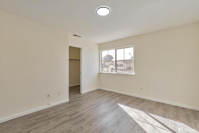 unfurnished bedroom with a closet, a spacious closet, and light hardwood / wood-style floors