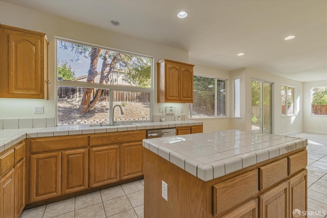 kitchen with tile countertops, plenty of natural light, sink, and a center island