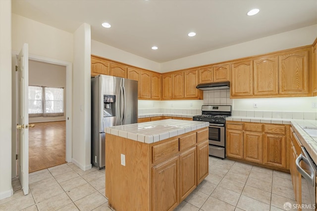 kitchen featuring stainless steel appliances, tile countertops, light tile patterned floors, and a kitchen island