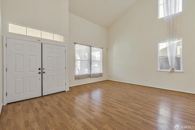 foyer entrance featuring high vaulted ceiling, a wealth of natural light, and light hardwood / wood-style floors