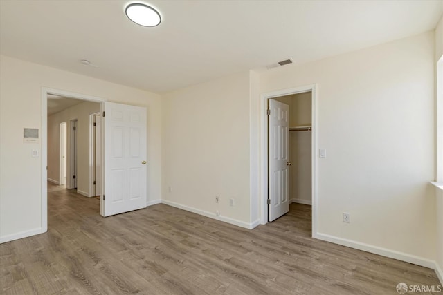 unfurnished bedroom featuring light hardwood / wood-style floors, a closet, and a walk in closet