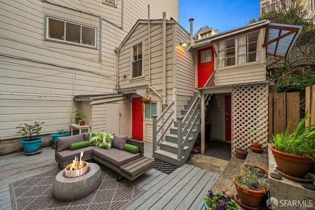 back of property featuring an outdoor living space with a fire pit, a deck, and fence