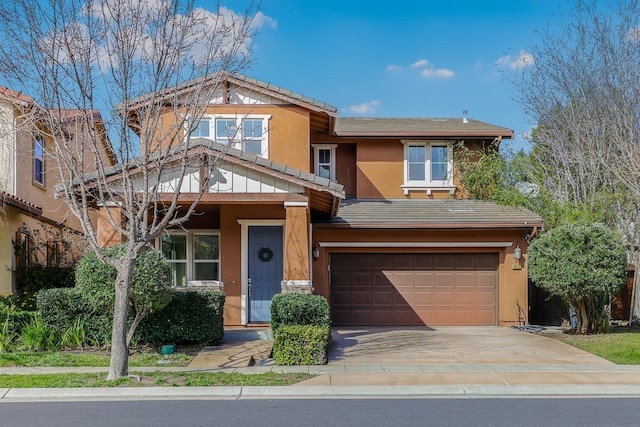 view of front of property featuring stucco siding, a tiled roof, concrete driveway, and a garage