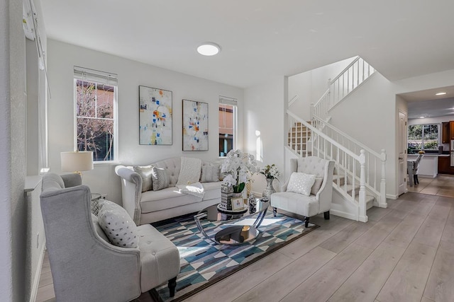 living room with baseboards, stairs, and light wood finished floors