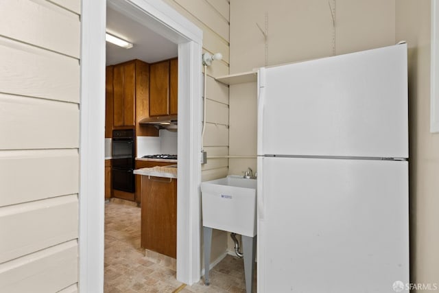 kitchen featuring black double oven and white refrigerator