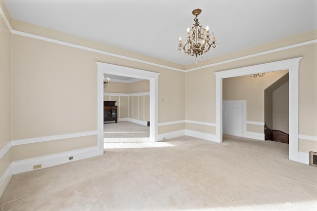 spare room with ornamental molding, a chandelier, and carpet flooring