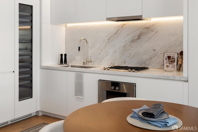1 Steuart Ln Unit 608, San Francisco, CA 94105 - kitchen with a sink, backsplash, white cabinets, wood finished floors, and range hood
