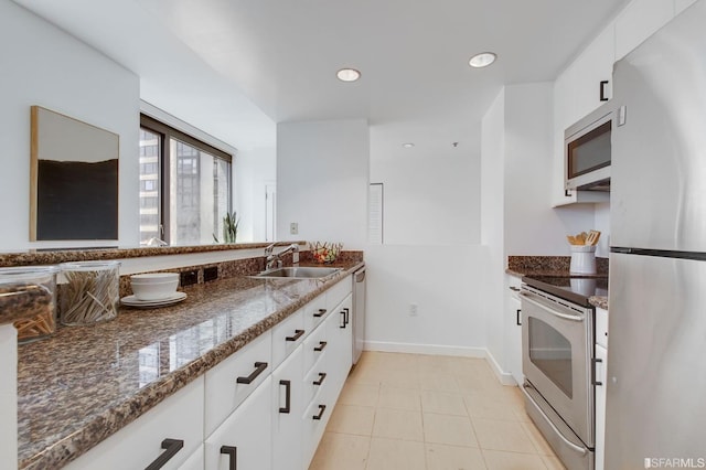 kitchen featuring appliances with stainless steel finishes, white cabinetry, dark stone counters, and sink