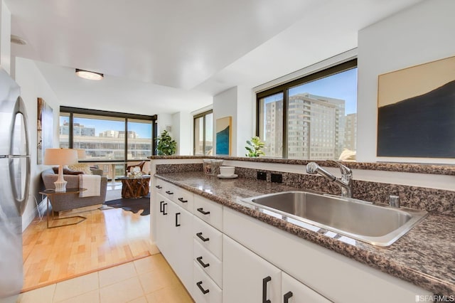 kitchen with white cabinets, plenty of natural light, light tile patterned floors, and sink