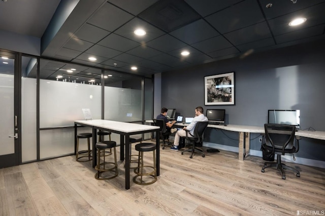 dining space featuring a drop ceiling, built in desk, and light wood-type flooring